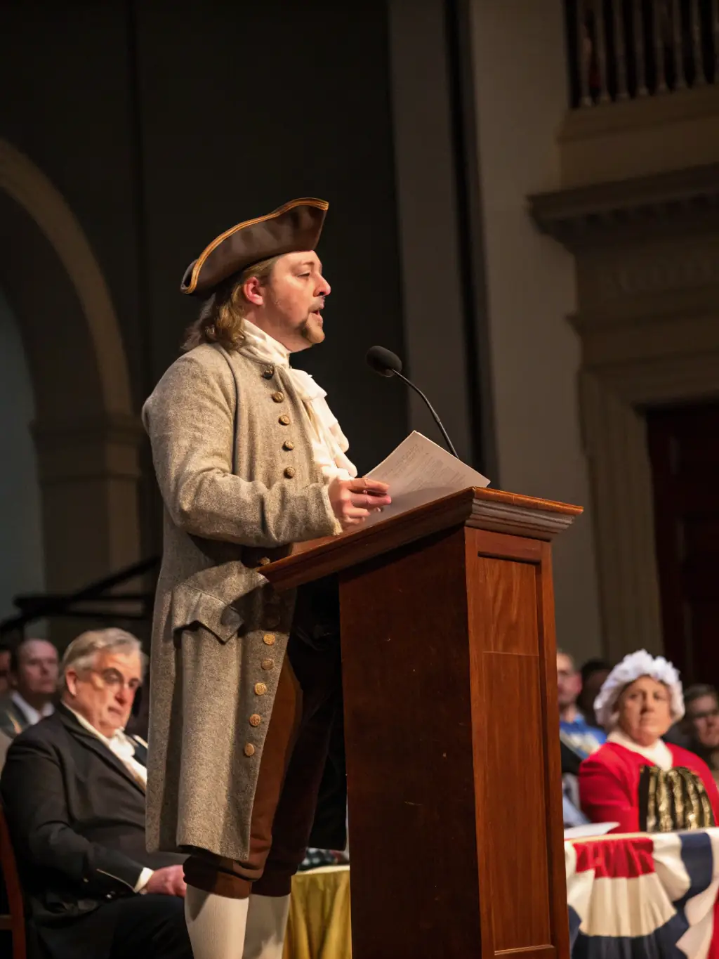 A photograph of a historical lecture in progress, with a speaker presenting on a historical topic and an audience listening attentively.